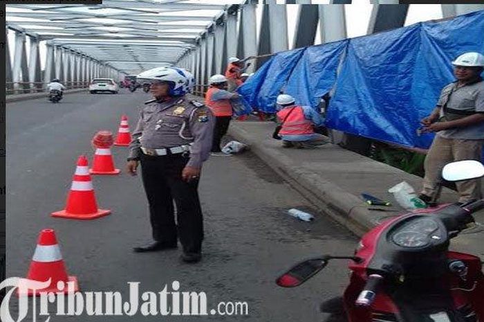 Pelaksana proyek memasang terpal pada satu sisi jembatan yang ada di barat jembatan cincin 