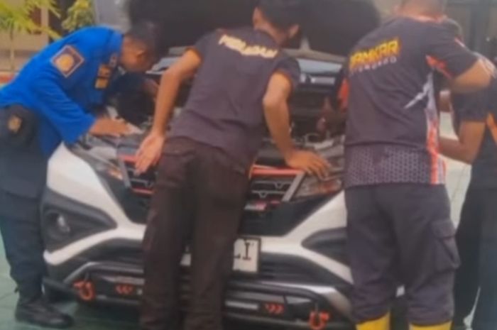 Petugas pemadam kebakaran berusaha mengevakuasi biawak dari dalam ruang mesin Toyota Rush di Pengadilan Agama Situbondo