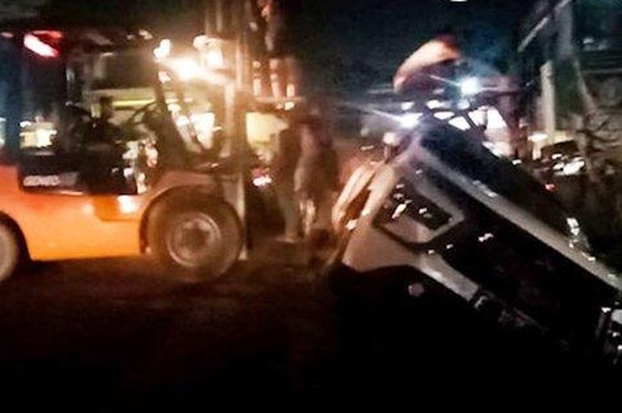 Forklift membantu mengangkat Mitsubishi Xpander dari dalam got di Jl Klodran Selatan, Colomadu, Karanganyar, Jawa Tengah
