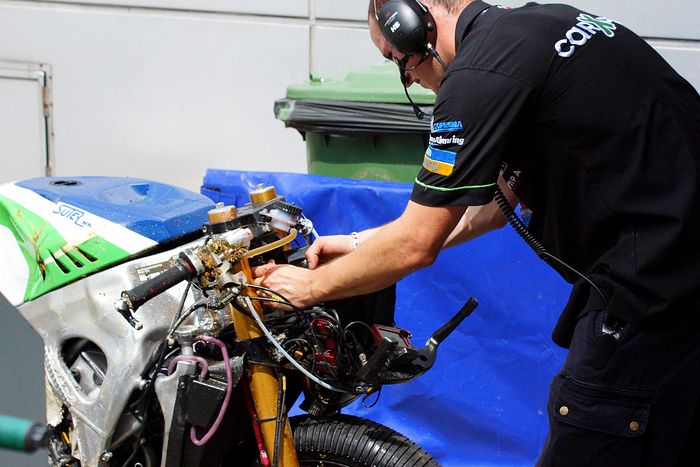 Salah satu mekanik menempelkan lakban di motor yang rusak