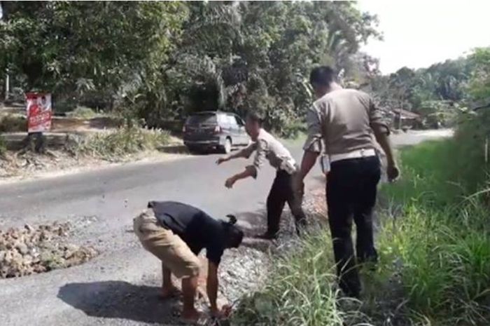 Polisi yang sedang menambal jalan berlubang