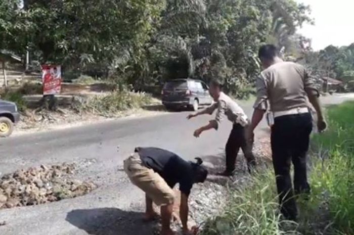 Potongan video yang diunggah pengguna Facebook Aconk Asfiyek mengenai polisi yang menambal jalan berl