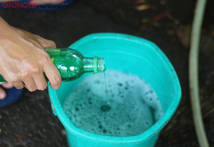Tuangkan sabun cuci piring ke ember berisi air untuk mencuci motor sendiri
