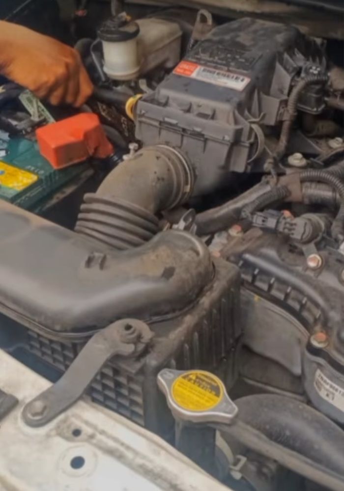 Petugas berusaha mengeluarkan seekor biawak yang bersembunyi di ruang mesin Toyota Rush 