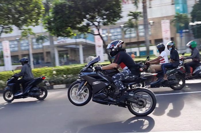 Salah satu biker melakukan wheelie di depan Senayan City, Jakarta Pusat pada Minggu (28/2/2021)