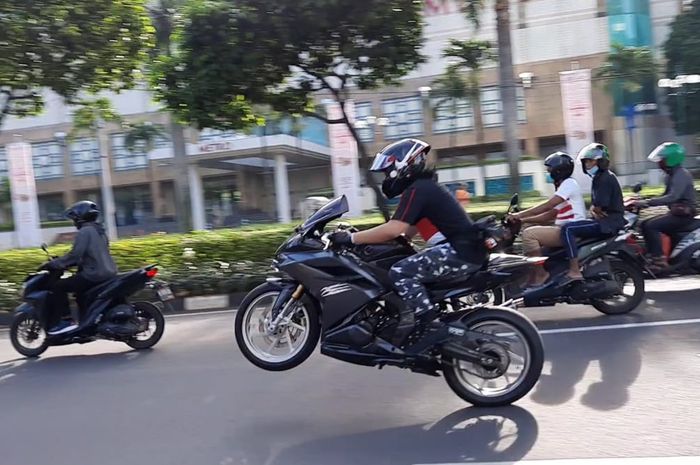 Salah satu biker melakukan wheelie di depan Senayan City, Jakarta Pusat pada Minggu (28/2/2021)