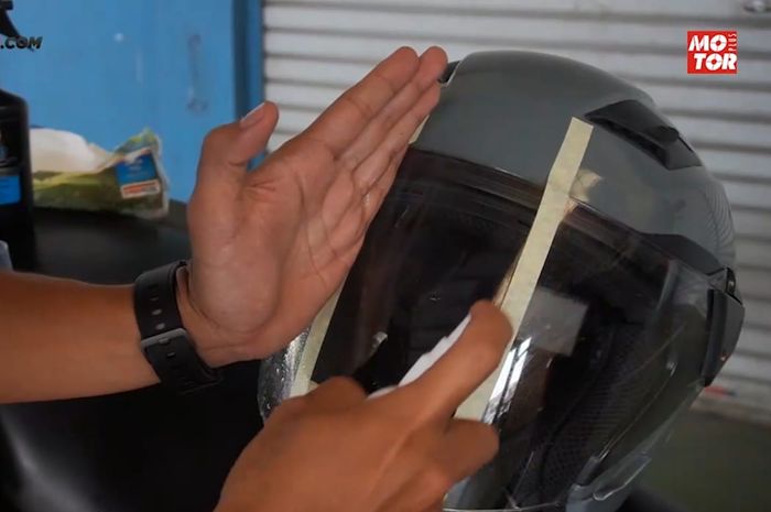 Semprot secara merata ke seluruh permukaan visor helm