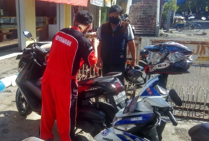 Mekanik Yamaha sedang melakukan servis motor konsumen, yang menggunakan layanan SKY