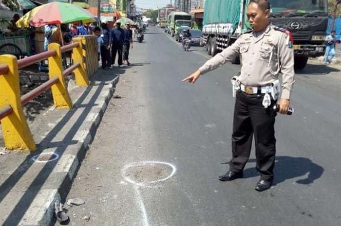 Polisi menunjukkan lokasi tewasnya pengendara motor yang gagal menyalip dari kiri truk tronton di kawasan Manyar Gresik, Rabu (10/7/2019). 