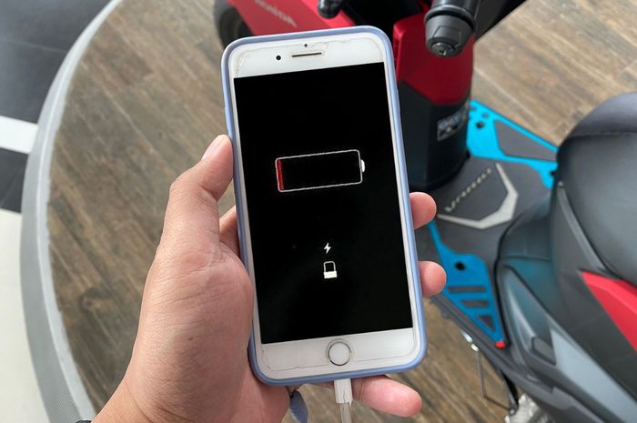 Ilustrasi ngecas handphone menggunakan power charger di motor