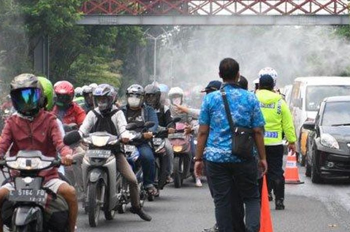 Petugas dari Dishub dan Polrestabes Surabaya melakukan penyemprotan disinfektan kepada kendaraan yang melintas di fronrage road Jalan Ahmad Yani yang merupakan salah satu pintu masuk ke Kota Surabaya, Jumat (27/3/2020)