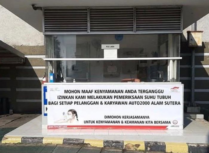 Spanduk pemberitahuan agar pelanggan melakukan pencekan suhu tubuh sebelum memasuki Auto2000.