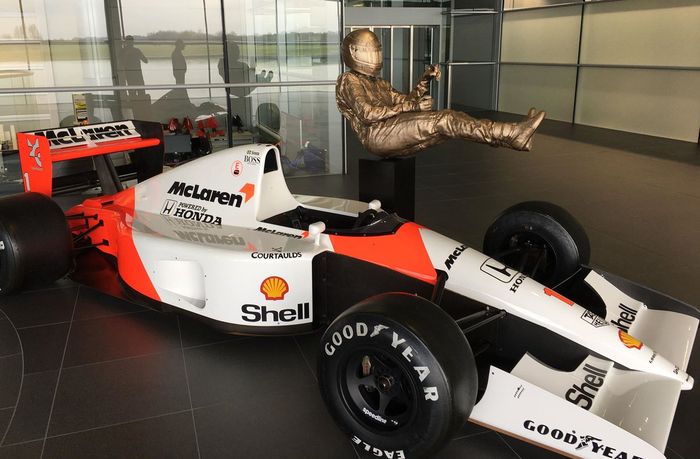 Patung Ayrton Senna di McLaren Techology Centre, di samping mobil McLaren MP4/6 yang membawanya juara dunia ketiga pada tahun 1991
