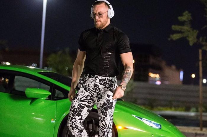 Conor McGregor yang luncurkan tendangan ke Dustin Poirier membelakangi Lamborghini Aventador Roadster.