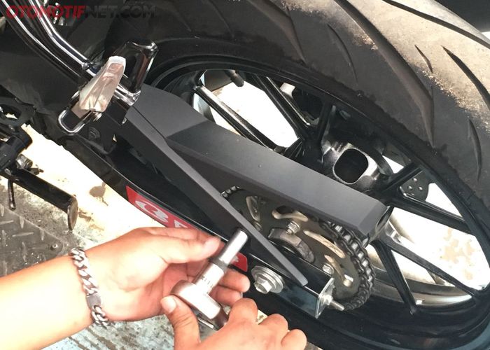 Lepaskan dua buah baut di tutup rantai