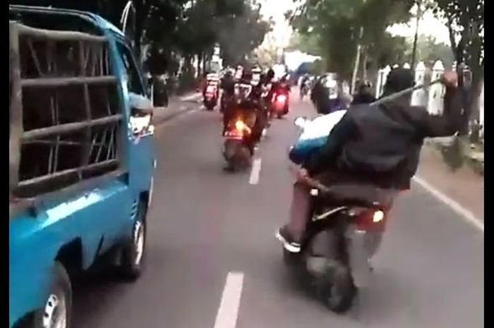 Naik motor boncengan ugal-ygala sambil acungkan Samurai di jalanan Kota Bandung