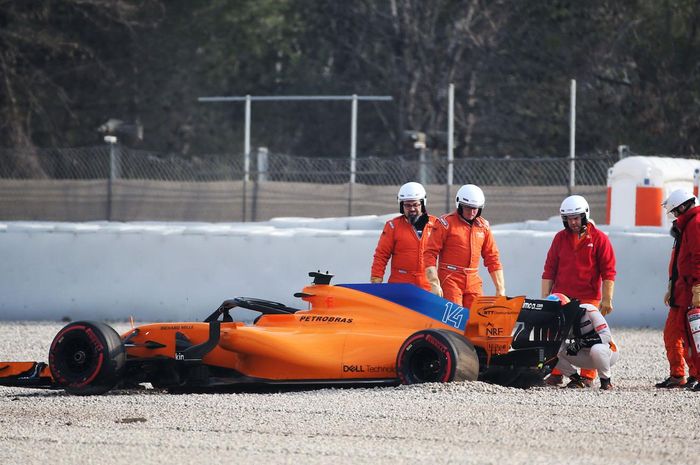 Fernando Alonso berjongkok mengecek mobilnya yang terhenti di gravel