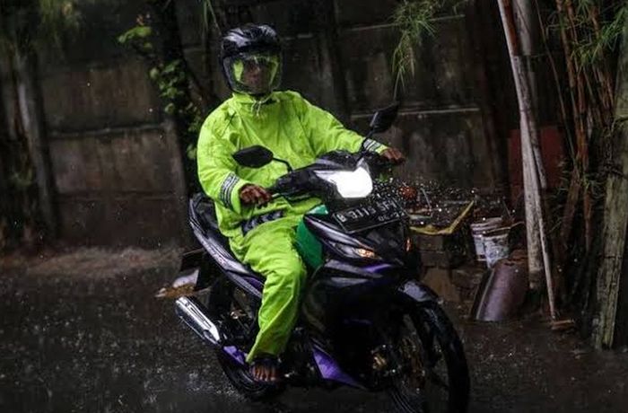 Ilustrasi berkendara memakai jas hujan