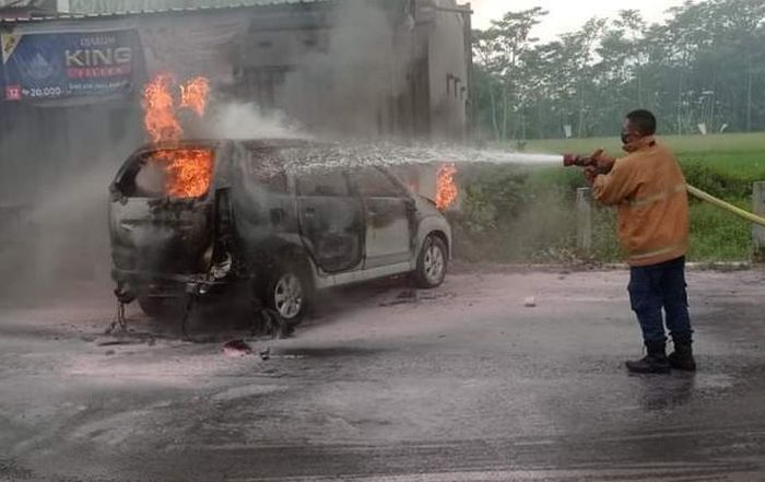 Petugas memadamkan api yang membakar Toyota Avanza di halaman SPBU Desa Petahunan, Sumbersuko, Lumajang