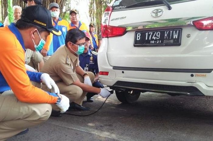 Petugas Sudin Lingkungan Hidup Jakarta Selatan saat melakukan uji emisi kendaraan roda empat yang melintas di depan Taman Makam Pahlawan, Kalibata, Pancoran, Selasa (24/7).