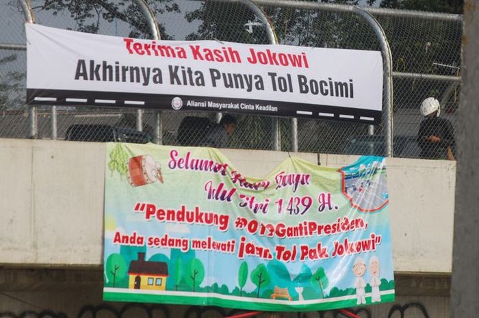 Spanduk bertuliskan Terima Kasih Jokowi, Akhirnya Kita Punya Bocimi dan Pendukung #2019GantiPresiden, Anda sedang melewati Jalan Tol Pak Jokowi terpasang di tol fungsional Bogor-Ciawi-Sukabumi (Bocimi), Senin (11/6/2018).