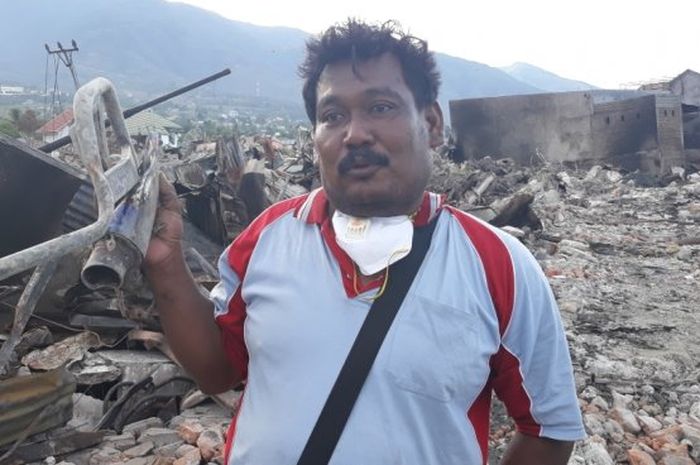 Rusli Abidin mengangkat sisa modifikasi motor yang ditemukan di puing-puing bencana Palu