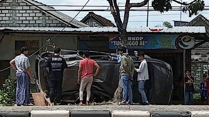 Warga mengerumuni Toyota Kijang Innova yang gelimpang usai sabet pohon dan tiang Telkom di desa/kecamatan Kapas, Babat, Lamongan, Jawa Timur akibat nyalip dari kiri