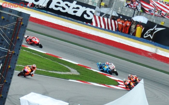 Marco Simoncelli berdampingan dengan pembalap tim Suzuki di tikungan pertama sirkuit Sepang pada MotoGP Malaysia 2011