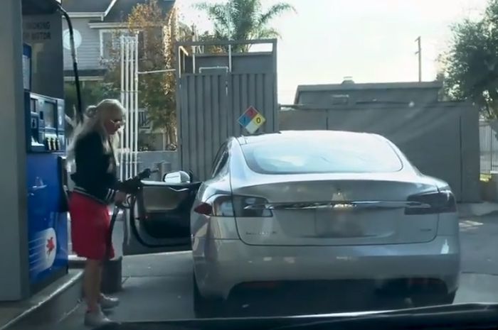 Wanita kebingungan dengan mobil Tesla Model S yang dikendarainya