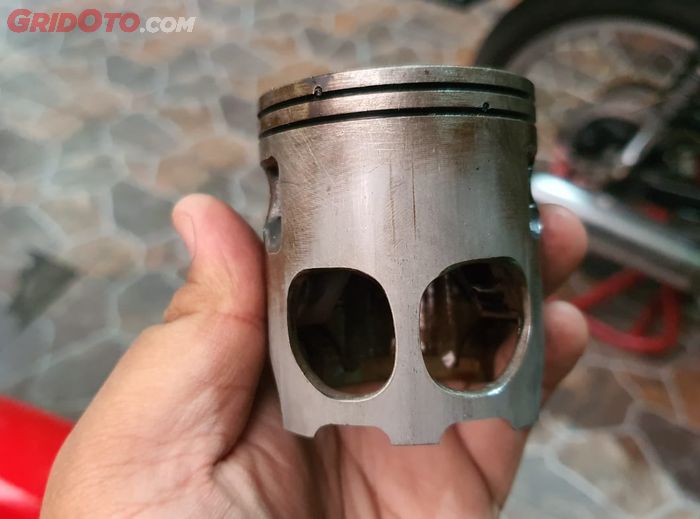 Piston motor 2-tak ada lubang untuk jalur bahan bakar ke crankcase