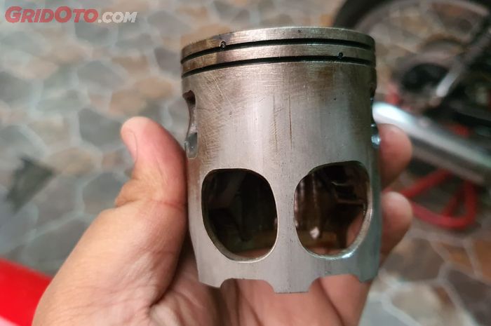 Piston motor 2-tak ada lubang untuk jalur bahan bakar ke crankcase