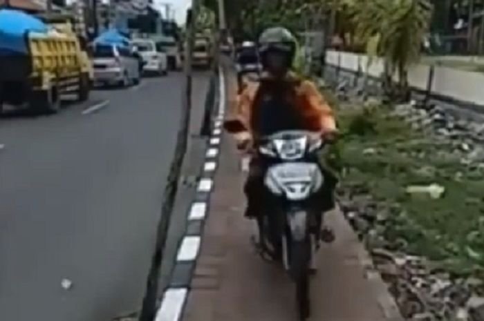 Pemotor yang melintas di trotoar dihadang turis di Bali.