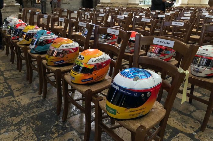 Helm pembalap berjejer di atas kursi di dalam katedral saat upacara pemakaman pembalap F2 Anthoine Hubert