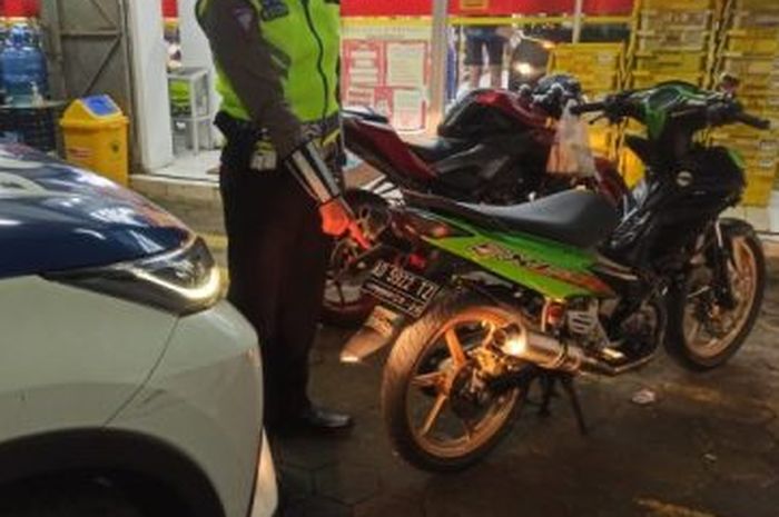 Ilustrasi petugas yang mengamankan motor berknalpot brong