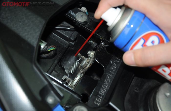 Semprot cairan penetran pada tuas pengungkit jok Honda BeAT yang terletak di bagian dalam