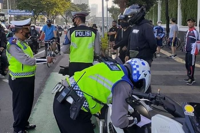 Beberapa anggota Polisi menilang pengendara motor di jalan